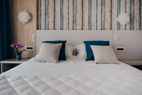 a bedroom with a white bed with blue and white pillows at Hotel Galassia Suites & Spa in Lido di Jesolo