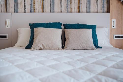 a white bed with blue pillows on top of it at Hotel Galassia Suites & Spa in Lido di Jesolo