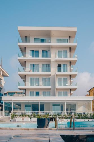 a large white building with a swimming pool in front of it at Hotel Galassia Suites & Spa in Lido di Jesolo