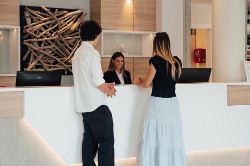 a man and two women standing at a counter at Hotel Galassia Suites & Spa in Lido di Jesolo