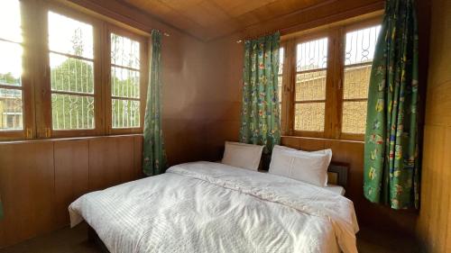 a bedroom with a bed and two windows at THE WILLOW HOUSE in Leh
