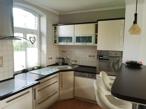a kitchen with white cabinets and black counter tops at Ferienwohnung am Sternhagener See in Lindenhagen