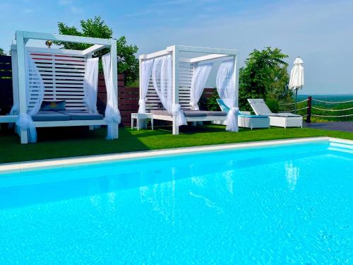 a swimming pool with two chairs and a swing and a pool at Love and Dream Élményvilla in Zalakaros