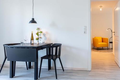 a dining room with a black table and chairs at Strandperle Appartements in Hasselberg
