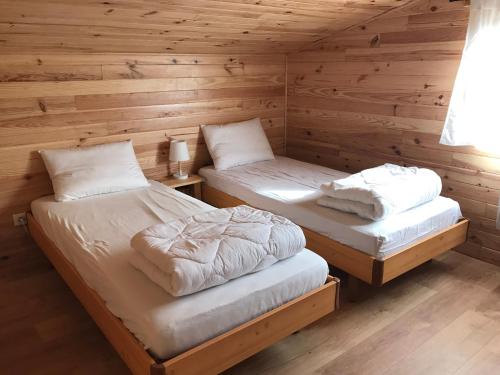 two beds in a room with wooden walls at Chalet 6/8 Pers avec jardin sur les pistes de ski in Saint-Léger-les-Mélèzes