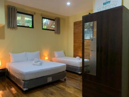a bedroom with two beds and a refrigerator at Mabini Hotel in Mambajao
