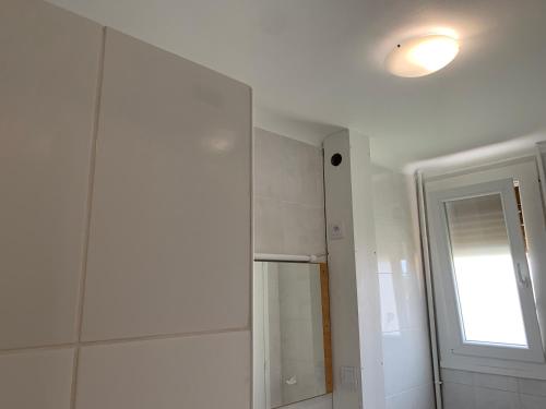a white bathroom with a refrigerator and a window at Superbe T3 spacieux, lumineux et sans vis-à-vis in Vigneux-sur-Seine