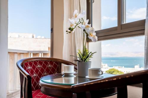 a table with two cups and a vase with flowers at Aviv Holiday Flat in Tiberias
