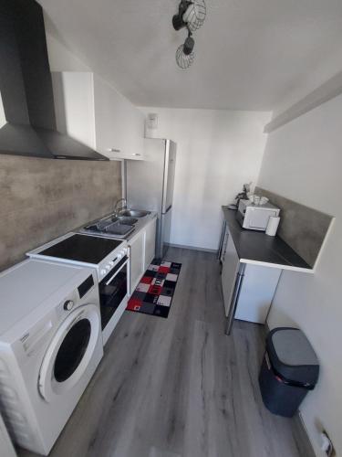 a kitchen with a stove and a washing machine at Appartement duplex 70m2 avec box privé à 150 m des telecabines in Briançon
