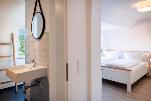 a bathroom with a sink and a bed with a mirror at Strandperle Appartements in Hasselberg