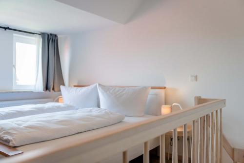 a bed with white sheets and pillows on it at Strandperle Appartements in Hasselberg