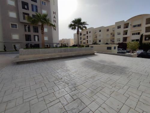 an empty parking lot with palm trees and buildings at Ideal Appart El Wahat VIP in El Aouina
