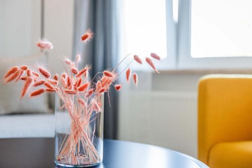 a vase filled with red flowers on a table at Strandperle Appartements in Hasselberg