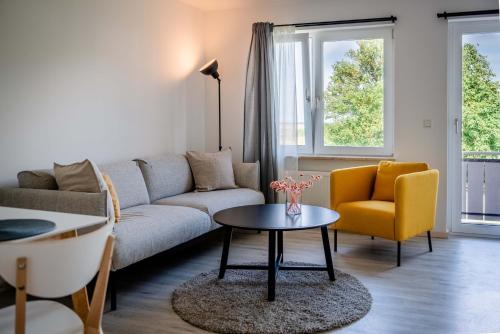 a living room with a couch and a table and a chair at Strandperle Appartements in Hasselberg