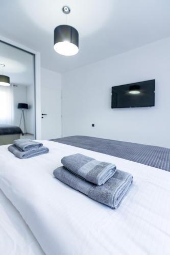a white bed with towels on top of it at Apartmani Gala Foča in Foča