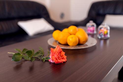 a table with a plate of oranges and a flower on it at Apartmani Gala Foča in Foča