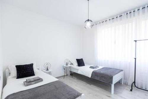 a white bedroom with two beds and a window at Apartmani Gala Foča in Foča
