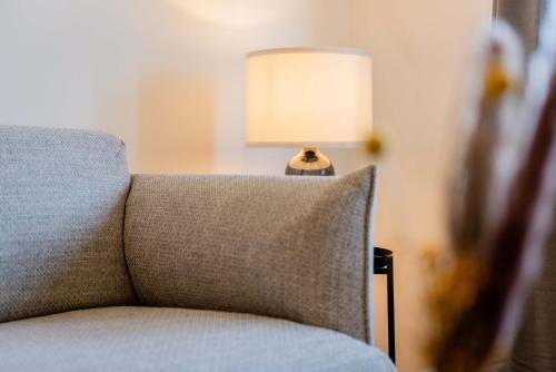 a lamp sitting next to a couch with a pillow at Strandperle Appartements in Hasselberg