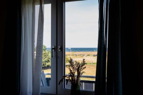 a window with a view of a field and the ocean at Strandperle Appartements in Hasselberg