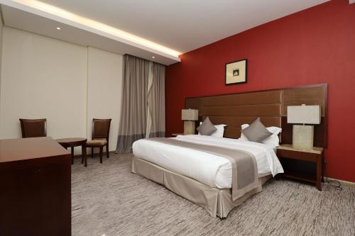 a bedroom with a large bed and a red wall at Maskan Almadinah in Dammam