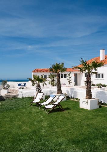 a group of chairs sitting in a yard next to a house at OUTPOST - Ocean Casitas in Azenhas do Mar
