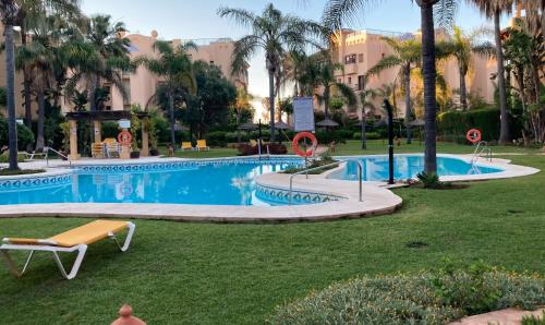 a swimming pool in a park with palm trees at Oasis Costalita Estepona I in Estepona