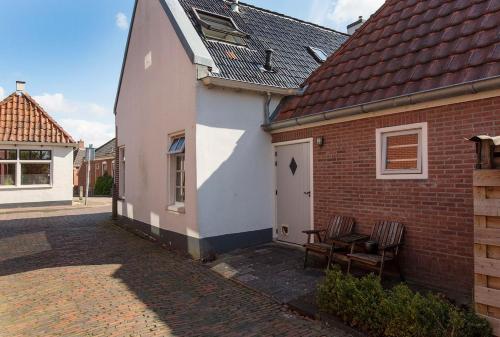 a white building with two chairs next to a brick building at Karakteristiek huis in centrum Winsum met nieuwe badkamer in Winsum