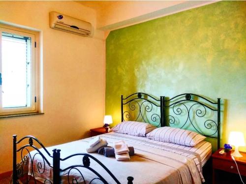 a bedroom with a bed with a green wall at Punto Verde B&B in Ardore Marina