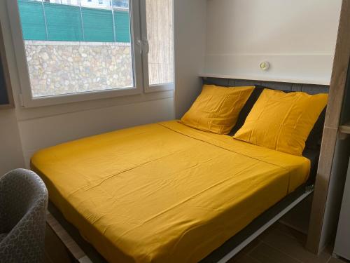 - un lit avec des draps et des oreillers jaunes dans une chambre dans l'établissement Votre écrin pour un agréable séjour à Marseille !, à Marseille