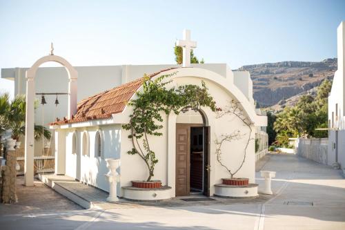 a small white church with a tree in front of it at Lindos White Hotel & Suites in Líndos