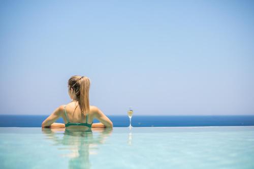 a woman in the water with a glass of wine at Lindos White Hotel & Suites in Líndos
