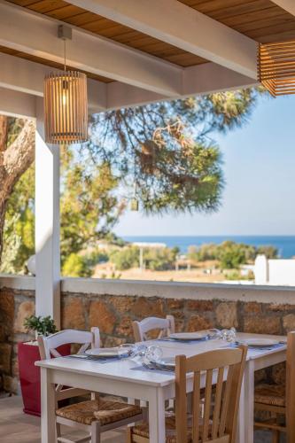 a white table with chairs and a chandelier at Lindos White Hotel & Suites in Líndos