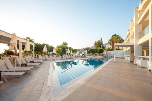 a pool at a hotel with chairs and umbrellas at Lindos White Hotel & Suites in Líndos