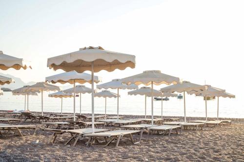 a group of tables and umbrellas on a beach at Lindos White Hotel & Suites in Líndos