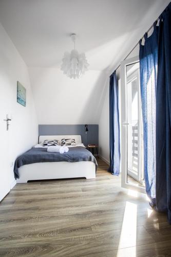 a white bedroom with a bed and a window at Domki Akacjowa Friends&Family Wellness in Łeba