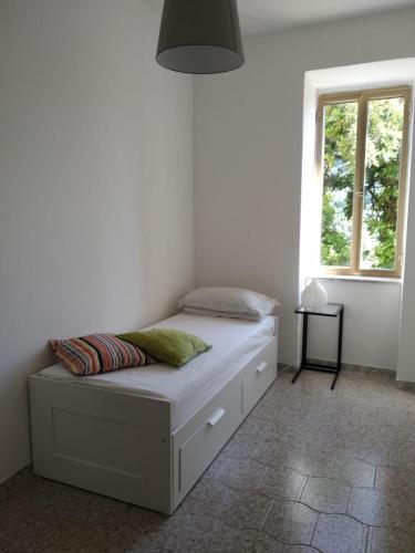 a bed in a white room with a window at Appartamenti vistAmare - La casa del vento in Vibonati