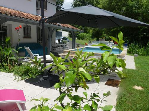 un patio avec un parasol et une piscine dans l'établissement Toki Eder chez Marisol, piscine chauffée, décoration soignée et océan à 15 minutes entre Bayonne et Hossegor, à Saint-Martin-de-Seignanx