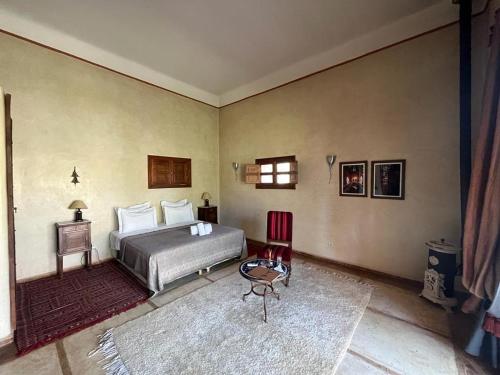 a bedroom with a bed and a red chair at Jnane Allia in Douar Soukkane