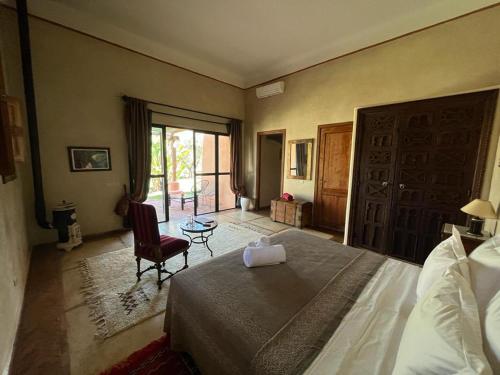 a bedroom with a bed and a chair and a window at Jnane Allia in Douar Soukkane