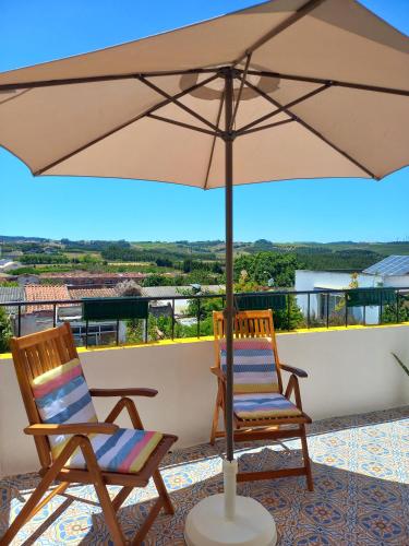 two chairs and an umbrella on a balcony at The Sweet Lemon 3 in Bombarral