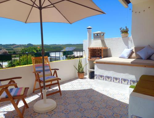 a patio with an umbrella and a chair and a bed at The Sweet Lemon 3 in Bombarral