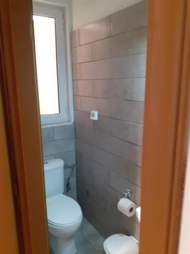 a bathroom with a toilet and a window at Alex Central City Accommodation in Lávrion