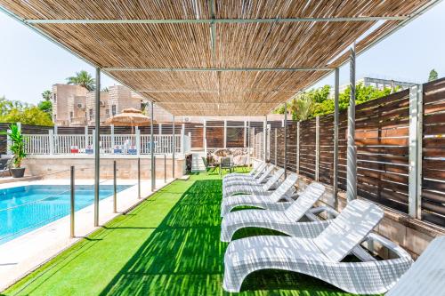 a row of white lounge chairs sitting on a deck next to a pool at Emily's Hotel in Tiberias