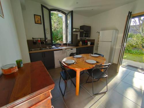 a kitchen with a wooden table and two chairs at Appartement 4/6 pers, jardin, 6 km de la plage in Saint-Julien-en-Born