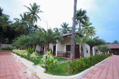 a building with palm trees in front of it at Royal Destiny Resort in Malaiyāndipattanam