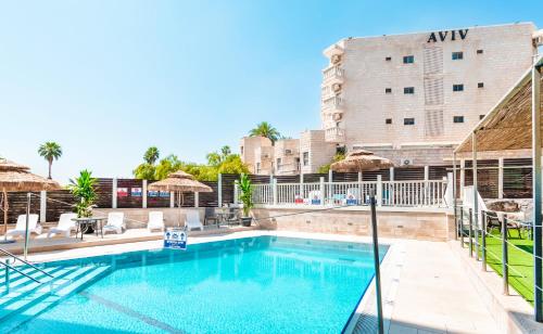 a swimming pool with a hotel in the background at Emily's Hotel in Tiberias