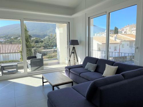 a living room with a blue couch and large windows at HERETAT - Casa con garaje a 5 minutos del centro in Cadaqués