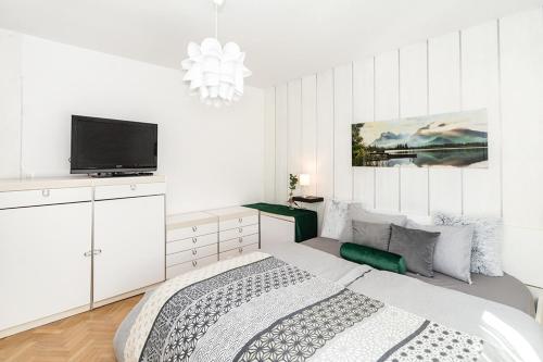 een witte slaapkamer met een bed en een flatscreen-tv bij Family Apartment Magnolia - Free Private Parking in Ljubljana