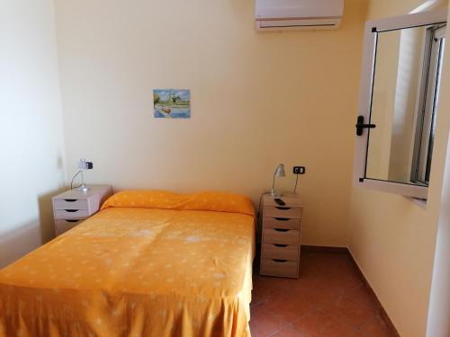 アシェーアにあるIl Mare di Eleaのベッドルーム1室(オレンジ色のベッドカバーと鏡付きのベッド1台付)