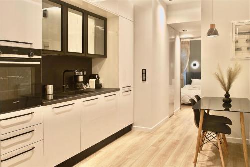 a kitchen with white cabinets and a table and a bedroom at Athelia Athens in Athens